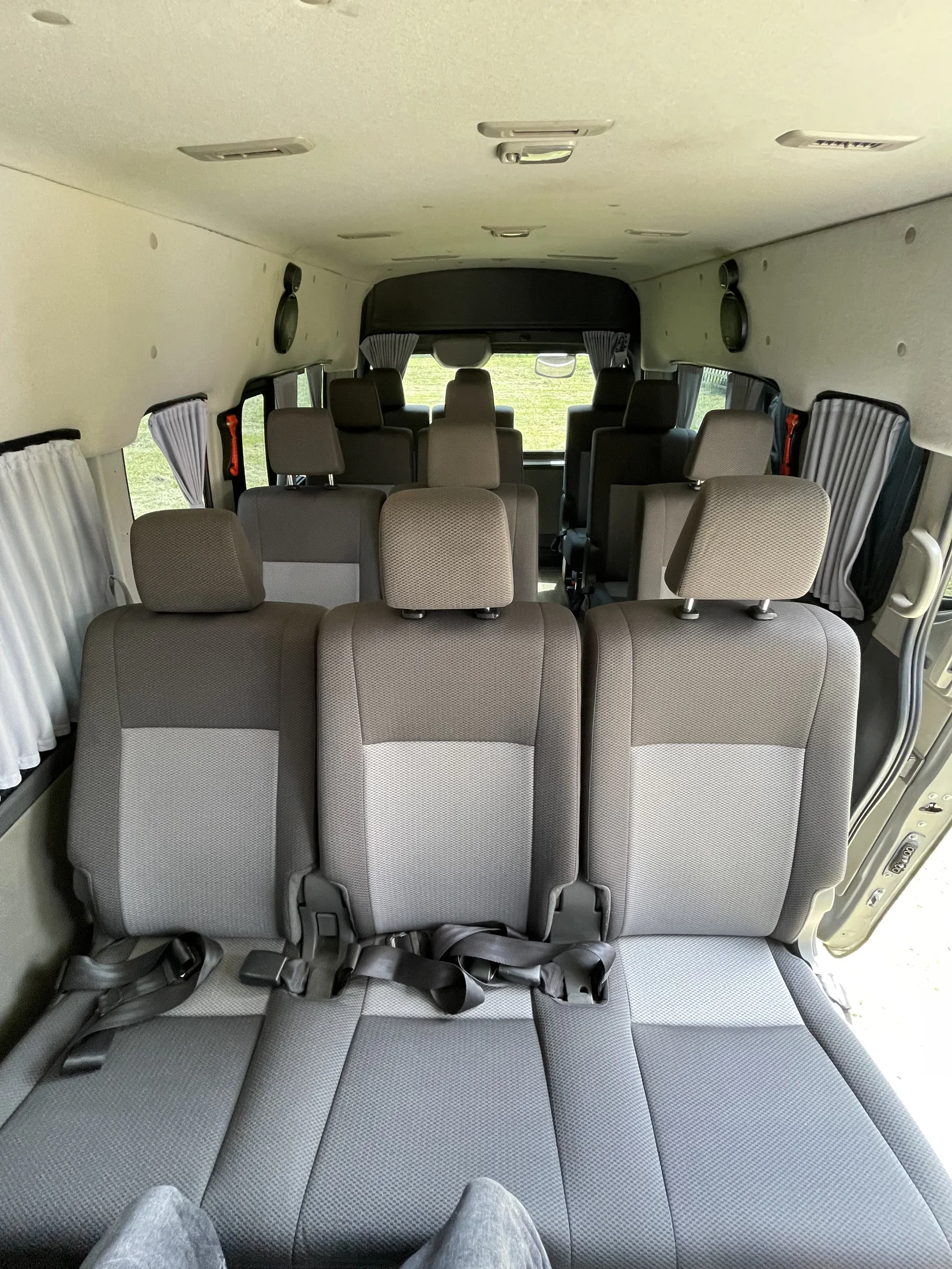 Inside FunFlights' Executive Tour Van — three rows of cloth seating with curtained windows.